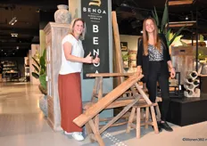 Kelly van Hoof en Maaike van de Kruys poseren bij teakbankjes, nieuw in het assortiment van Benoa. "Ze zijn heel populair", aldus de dames.